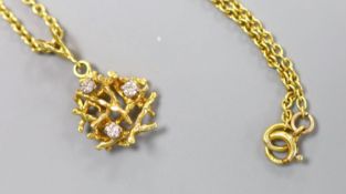 A modern yellow metal and three stone diamond set rustic pendant, 15mm, on a 18ct chain, 45cm,gross
