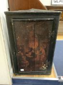 A late 18th century East Anglian lacquered hanging corner cupboard, painted with an interior scene