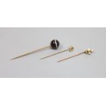 Three assorted early 20th century yellow metal and gem set stick pins,including banded agate,