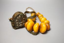 An early 20th century Tibetan and white metal portable shrine and a simulated amber Buddhist rosary