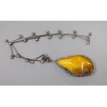 A stylish white metal and amber pebble set pendant necklace,76cm, gross weight 88 grams.