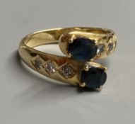 A modern 18ct and two stone sapphire crossover ring, with diamond set shoulders, size P, gross 5.4