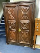 A large fruitwood double wardrobe / armoire, with twin carved panelled doors below a dentil frieze,