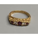 A modern Victorian style 18ct gold, three stone ruby and two diamond set half hoop ring, size N,