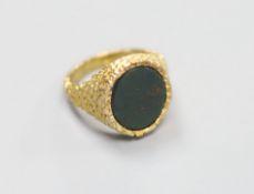 A modern 9ct gold and bloodstone set oval signet ring, with textured setting, size Q,gross 10.7