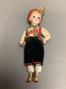 A bisque doll with boots and large glass eyes, height 15cm
