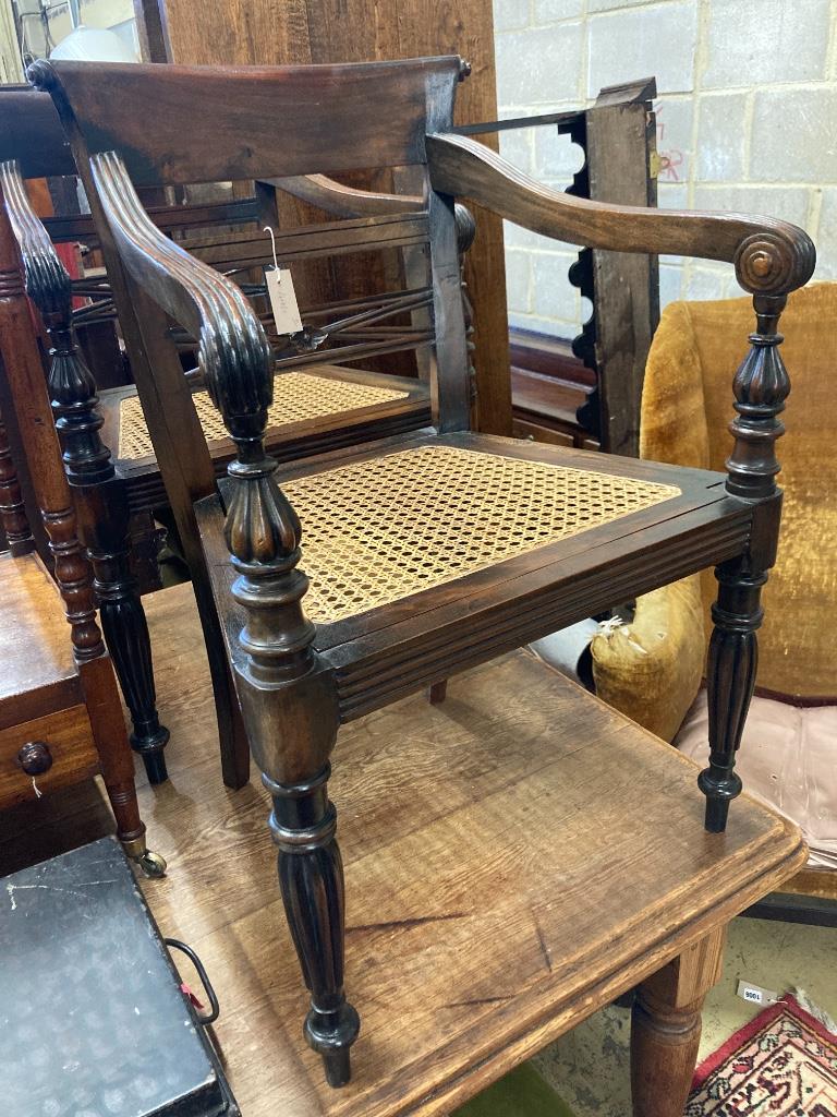 A pair of carved hardwood Anglo Indian elbow chairs with cane seats