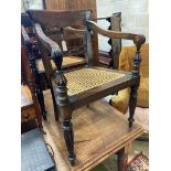 A pair of carved hardwood Anglo Indian elbow chairs with cane seats