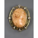 An early 20th century yellow and white metal mounted oval coral pendant brooch, carved with the