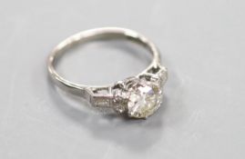 A white metal(stamped platinum) and single stone diamond ring with baguette and round cut diamond