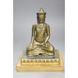 A South East Asian engraved and polished bronze figure of a seated deity,on stepped giltwood