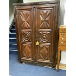 A large fruitwood double wardrobe / armoire, with twin carved panelled doors below a dentil frieze,