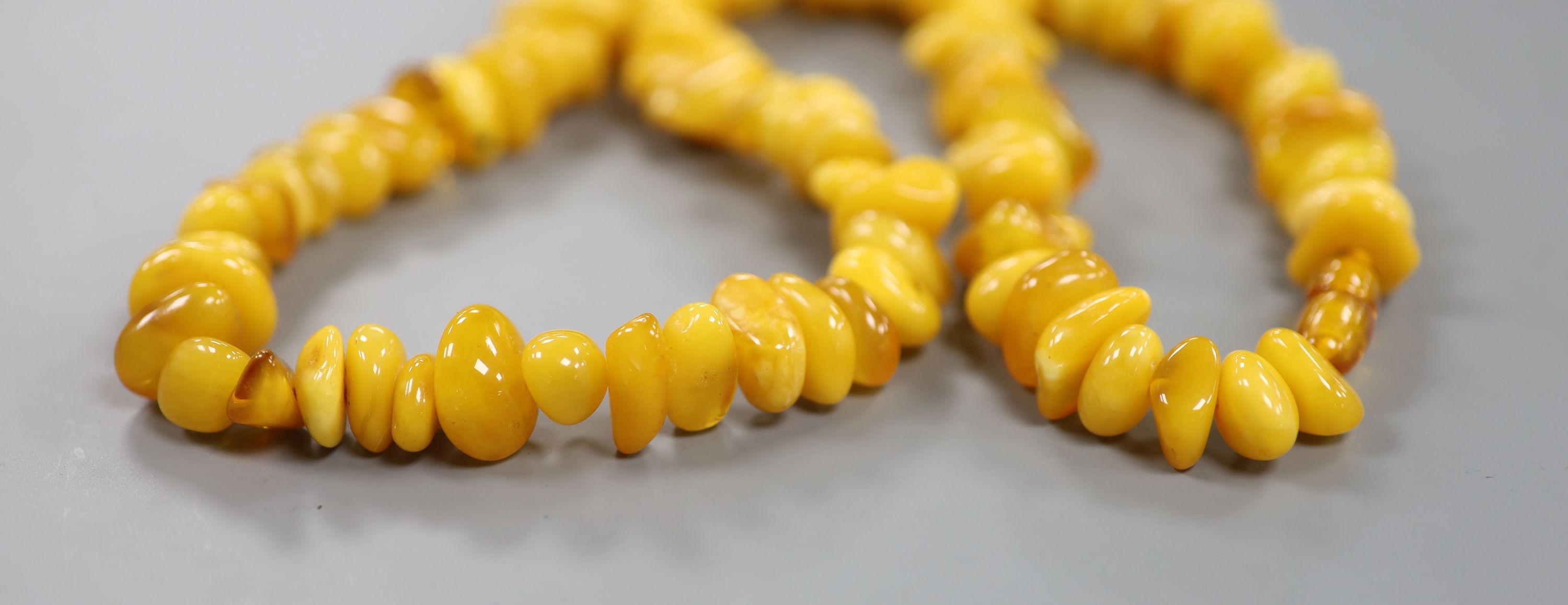 A single strand amber pebble necklace, approximately 66cm, gross weight 75 grams.