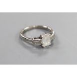 A white metal and emerald cut single stone diamond ring, with baguette cut diamond set shoulders,