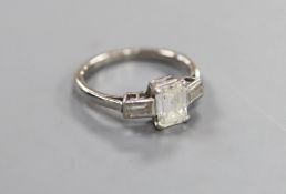 A white metal and emerald cut single stone diamond ring, with baguette cut diamond set shoulders,