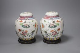 A pair of Chinese famille rose jars and covers, late 19/early 20th century, 15.5cm, on hardwood