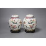 A pair of Chinese famille rose jars and covers, late 19/early 20th century, 15.5cm, on hardwood