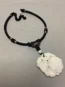 A Chinese pale grey jade carved and pierced pendant depicting two monkeys on a loquat,on black cord