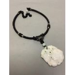 A Chinese pale grey jade carved and pierced pendant depicting two monkeys on a loquat,on black cord