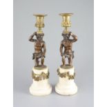 A pair of 19th century bronze and ormolu figural candlesticks,with kneeling figures raising urns,