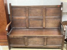 A mid 18th century panelled oak hinged box seat settle, length 148cm, depth 56cm, height 122cm