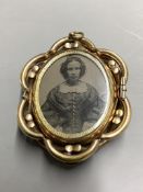 A Victorian pinchbeck and enamel revolving oval mourning brooch, with plaited hair below a glazed