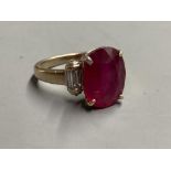 A modern yellow metal (stamped 750) and oval cut single stone ruby dress ring, with baguette cut