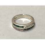 A platinum, emerald and diamond ring,channel set with two rows of emeralds and diamonds (some