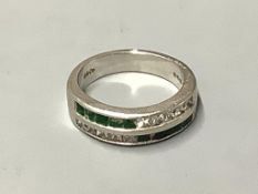 A platinum, emerald and diamond ring,channel set with two rows of emeralds and diamonds (some