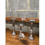 Set of three nickel plated candle stands with glass shades, height 51cm