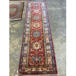 A Kazak red ground runner with geometric motifs, 274 x 80cm