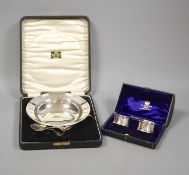 A cased christening dish with associated pusher and spoon, together with a cased pair of silver