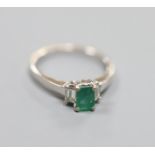 A modern white metal (engraved 750), emerald and diamond set three stone ring, size P,gross weight