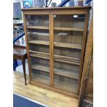 A late Victorian oak two door glazed bookcase, width 112cm, depth 29cm, height 152cm