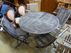 A teak garden table, 125cm diameter and four matching chairs, all folding