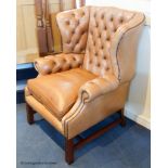 A George III style buttoned tan leather wingback armchair