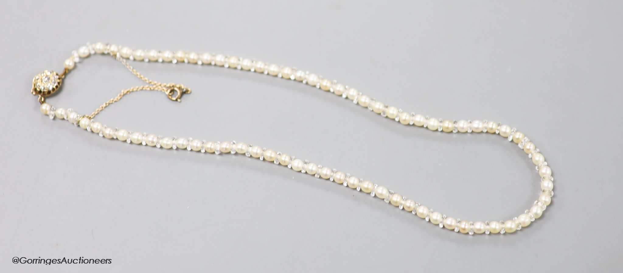 An early 20th century single strand cultured pearl and paste spacer necklace with diamond cluster
