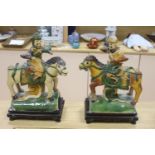 A pair of Chinese Ming sancai ‘horse and rider’ ridge tiles, height 38cm on wooden stand