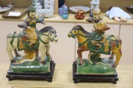 A pair of Chinese Ming sancai ‘horse and rider’ ridge tiles, height 38cm on wooden stand