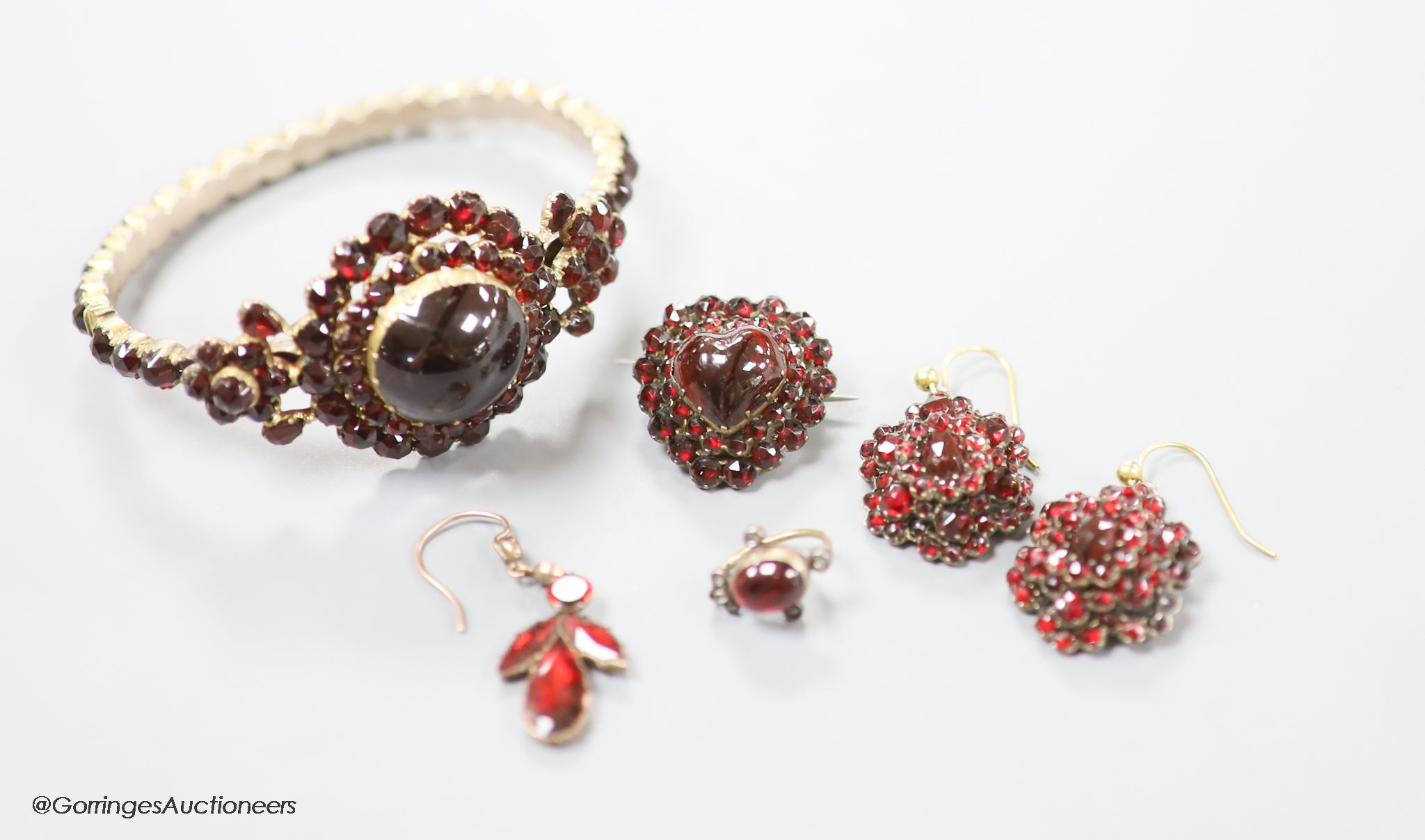 A Victorian gilt metal, facet and cabochon cut garnet set hinged bracelet, a pair of similar