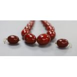 A single strand simulated oval amber bead necklace, 52cm and a pair of similar earrings, gross 94