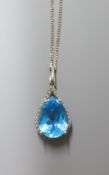 A modern white metal (stamped 9k), blue topaz and diamond chip set pendant, 29mm, on a 9ct white
