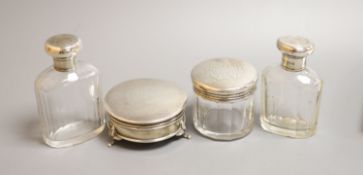 Three silver mounted glass toilet bottles and a George V silver mounted circular trinket box by