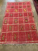 A Moroccan red ground rug,decorated with geometric panels, 240 x 140cm