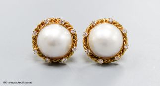 A modern pair of yellow metal (stamped 14k), mabe pearl set earrings, with diamond set rope twist