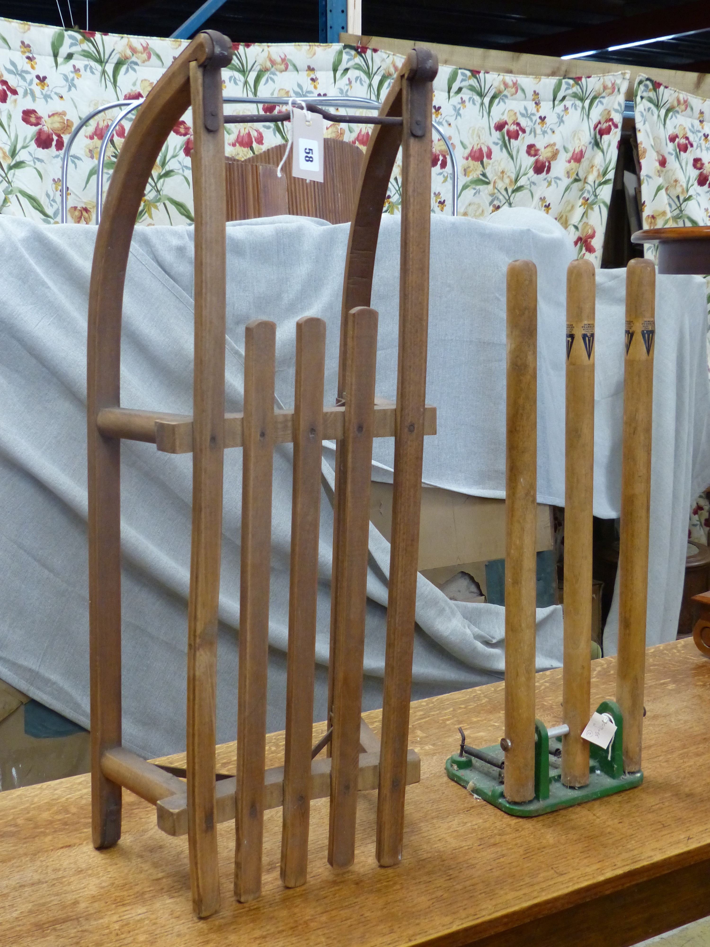 A vintage sled, a set of practise cricket stumps on sprung cast iron base