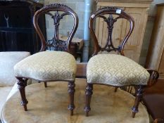 A set of four Victorian carved walnut balloon back dining chairs