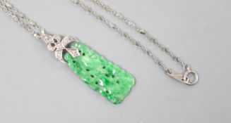 A 1920's white metal and diamond mounted carved jade pendant, numbered 'G 320 1', 4cm, on a