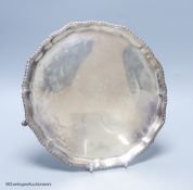 A circular silver salver with shaped gadrooned edge, on three hoof feet,London 1922, S W Smith &
