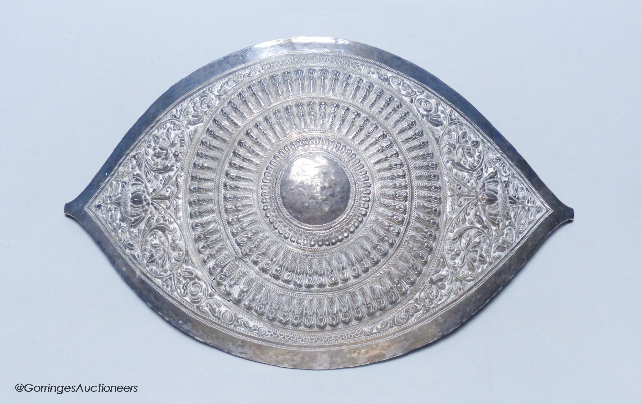 A Chinese Straits large white metal belt buckle, of curved navette form,having embossed foliate